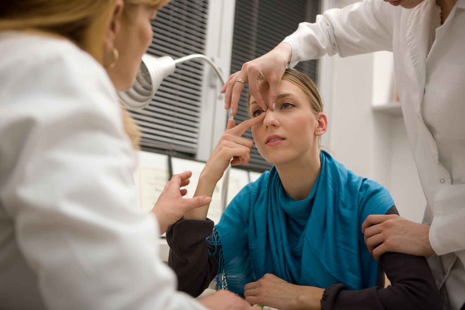 woman receiving a rhinoplasty consultation by two plastic surgeons