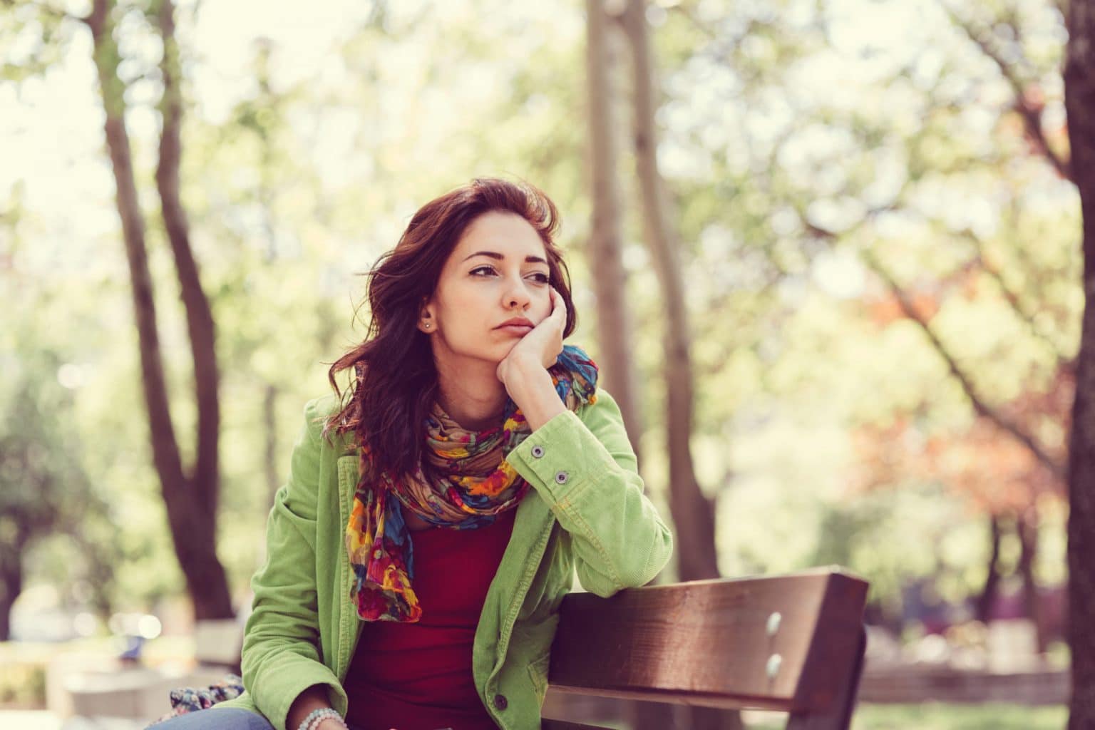 Woman sitting on a park bench with an uninterested expression.