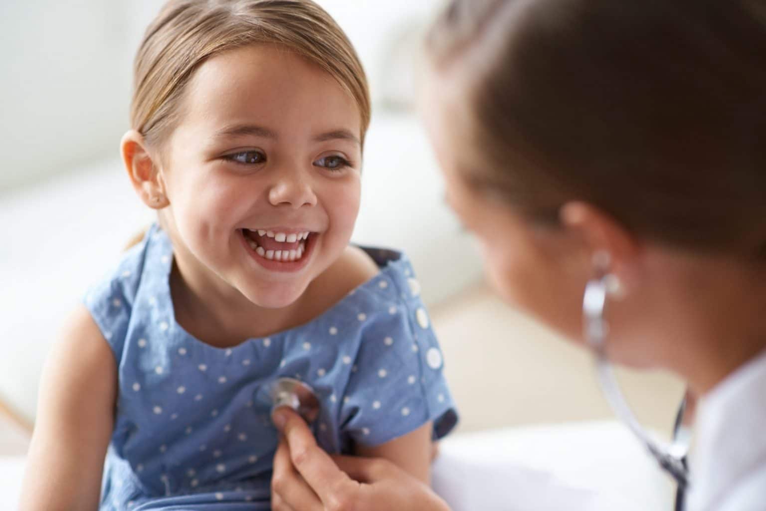 A female pediatric patient has her lungs checked by a doctor for signs of asthma.